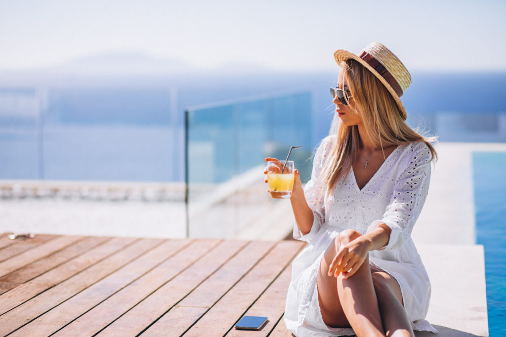 Young woman drinking juice bu the pool Young woman drinking juice bu the pool